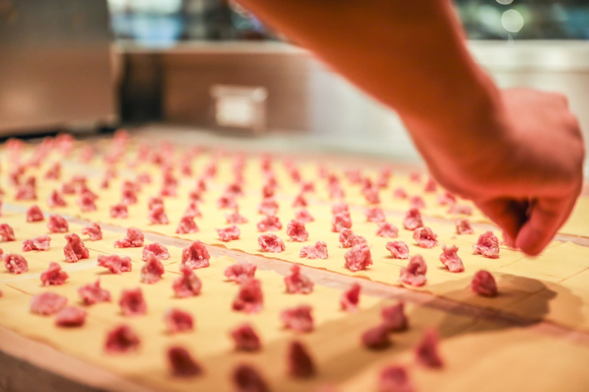 Rows of hand-shaped filled pasta on a wooden board